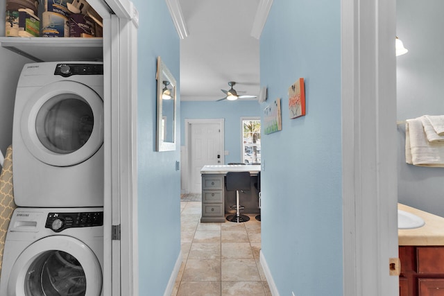 clothes washing area with ceiling fan, ornamental molding, stacked washer / dryer, and light tile patterned floors