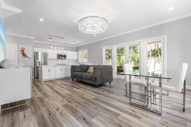 living room with an inviting chandelier, light hardwood / wood-style flooring, and ornamental molding