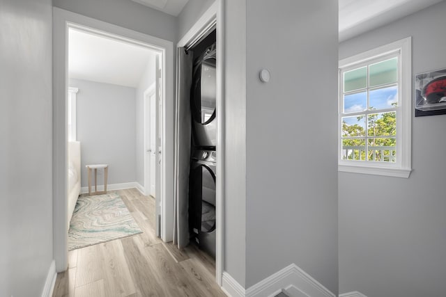 corridor with light hardwood / wood-style flooring and stacked washer and clothes dryer