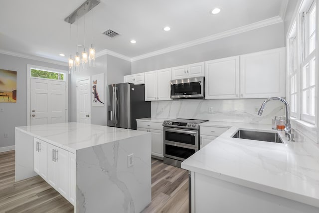 kitchen featuring sink, stainless steel appliances, light stone countertops, a kitchen island, and decorative light fixtures