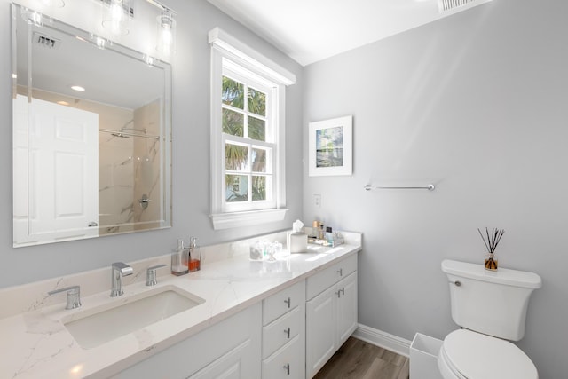 bathroom featuring a shower, hardwood / wood-style floors, vanity, and toilet