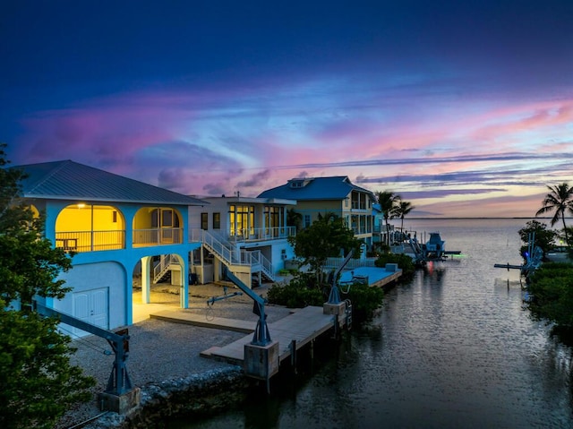 back house at dusk featuring a patio area and a water view