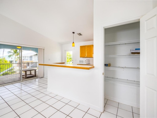 kitchen featuring lofted ceiling, light tile patterned floors, decorative light fixtures, and kitchen peninsula