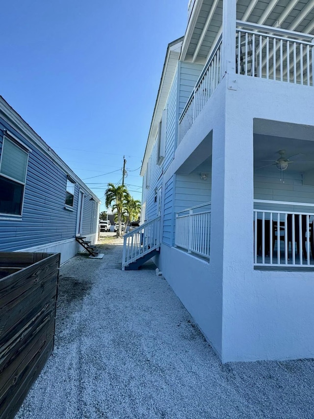 view of property exterior featuring a balcony, a ceiling fan, and stucco siding