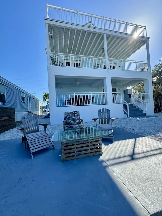 rear view of house featuring a balcony, a patio area, and stairs