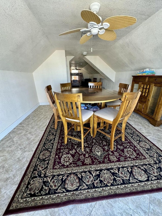 dining room with vaulted ceiling, a textured ceiling, baseboards, and ceiling fan