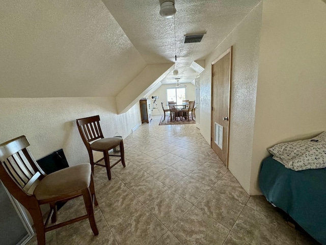 sitting room featuring lofted ceiling, visible vents, a textured ceiling, and a textured wall