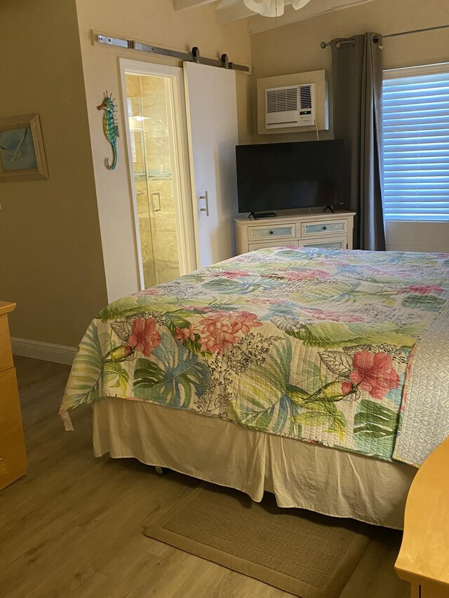 591 9th St, Key Colony, FL 33051 - bedroom with baseboards, wood finished floors, a barn door, and a wall mounted air conditioner