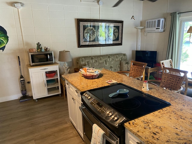 kitchen with light stone countertops, decorative light fixtures, a wall unit AC, and black / electric stove