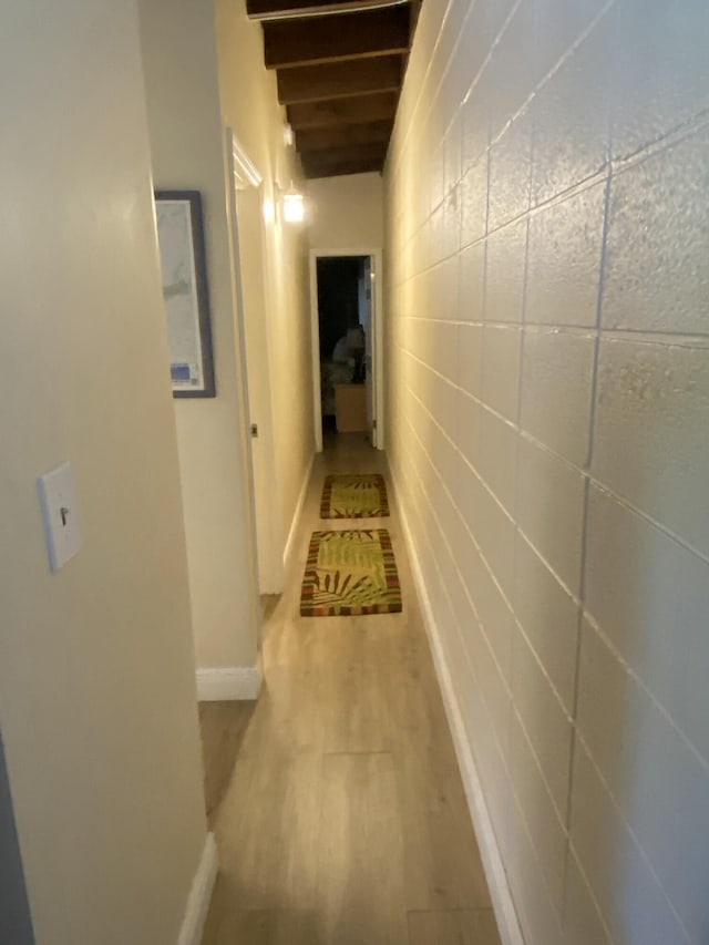 corridor with beamed ceiling and light hardwood / wood-style floors