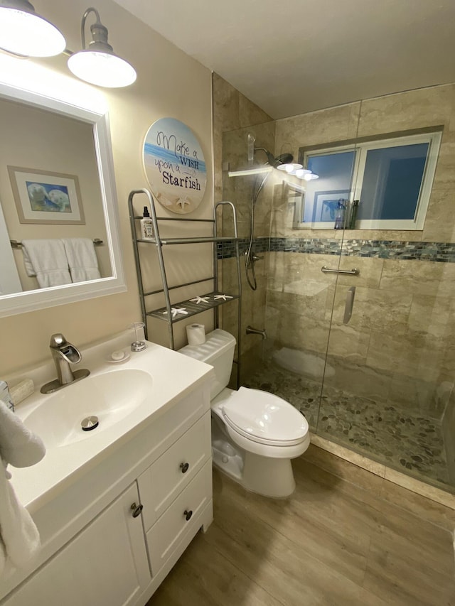 bathroom with a shower with door, vanity, wood-type flooring, and toilet