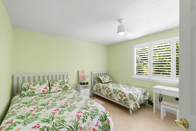 bedroom featuring ceiling fan, a textured ceiling, and light tile patterned flooring