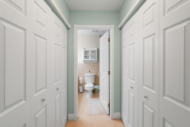 corridor with tile walls and light tile patterned flooring