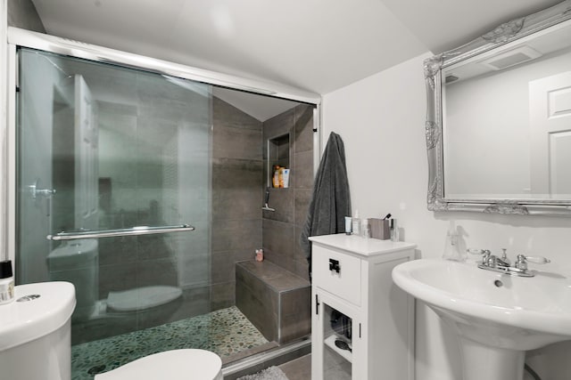 bathroom featuring sink, vaulted ceiling, a shower with shower door, and toilet