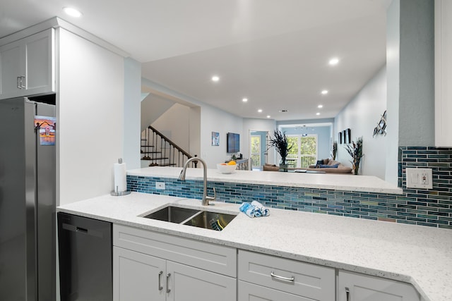 kitchen featuring sink, light stone counters, stainless steel refrigerator, dishwasher, and backsplash