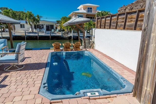 view of swimming pool with a water view and a patio area