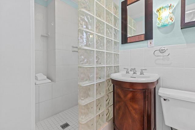 bathroom with vanity, toilet, tile walls, and a tile shower