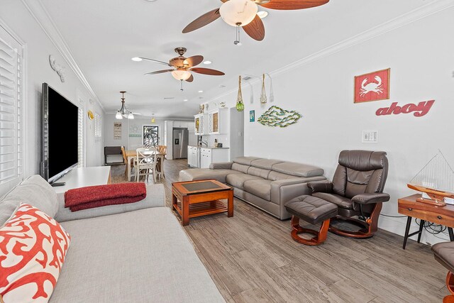 living room with ornamental molding, ceiling fan, and light hardwood / wood-style floors