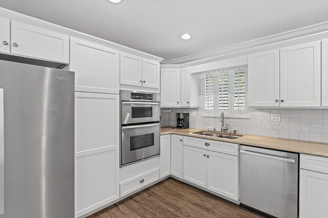 kitchen with dark hardwood / wood-style floors, white cabinetry, sink, decorative backsplash, and stainless steel appliances