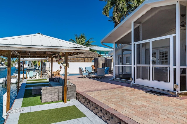 view of patio featuring a sunroom, outdoor lounge area, a boat dock, and a water view