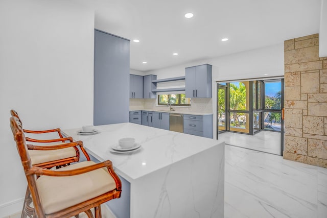 kitchen with sink, stainless steel dishwasher, a kitchen breakfast bar, kitchen peninsula, and decorative backsplash