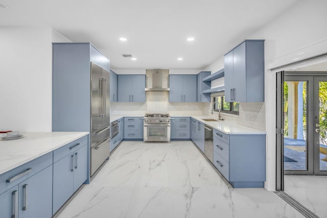 kitchen with sink, backsplash, premium appliances, and wall chimney exhaust hood