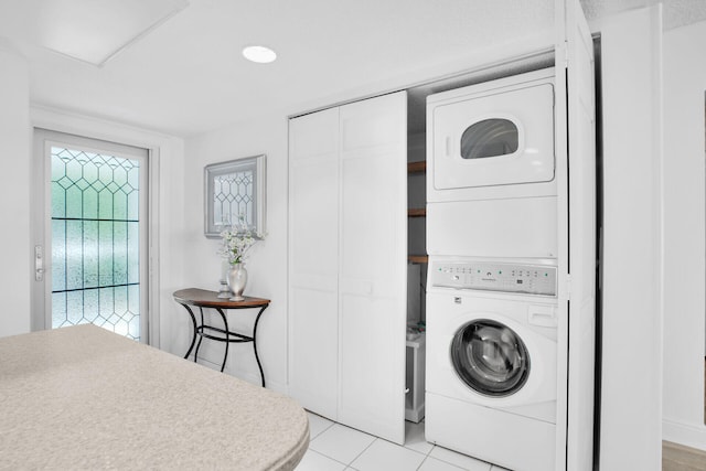 laundry room with light tile patterned flooring and stacked washer and clothes dryer