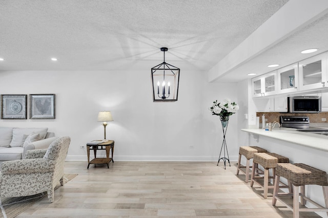 interior space with white cabinetry, appliances with stainless steel finishes, hanging light fixtures, and light hardwood / wood-style flooring