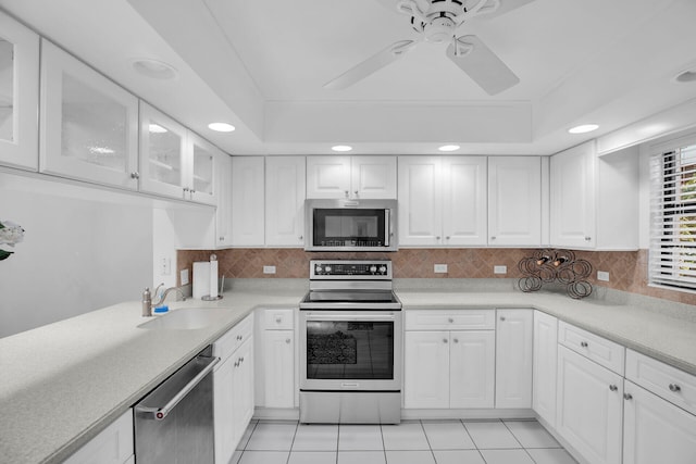 kitchen featuring stainless steel appliances, white cabinets, and a tray ceiling