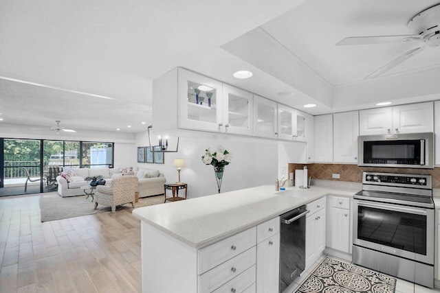 kitchen featuring light wood-type flooring, appliances with stainless steel finishes, ceiling fan, decorative backsplash, and white cabinets