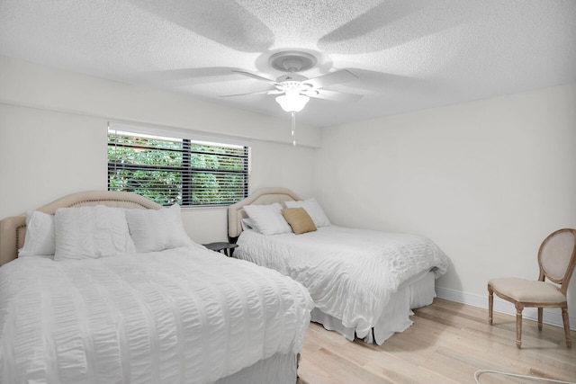 bedroom featuring ceiling fan, light hardwood / wood-style floors, and a textured ceiling