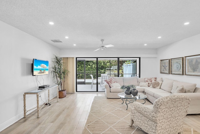 living room featuring ceiling fan, a textured ceiling, and light hardwood / wood-style floors