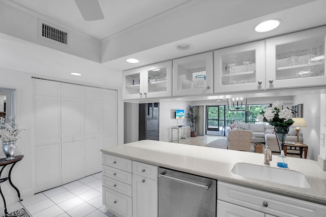 kitchen featuring light tile patterned flooring, sink, stainless steel dishwasher, and white cabinets