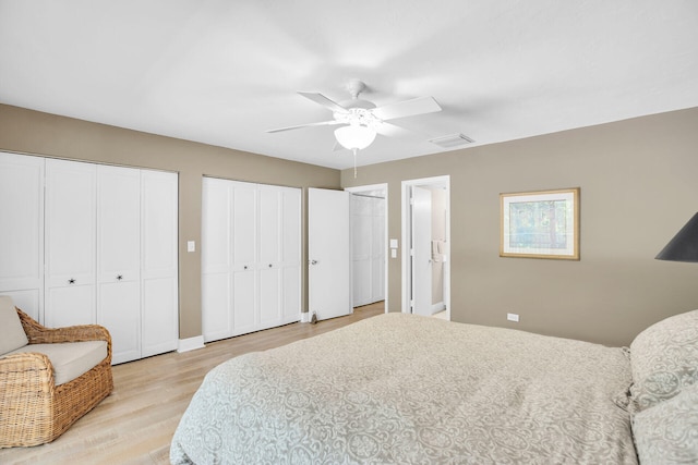 bedroom with two closets, ceiling fan, and light hardwood / wood-style flooring