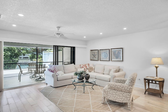 living room featuring ceiling fan, a textured ceiling, and light hardwood / wood-style flooring