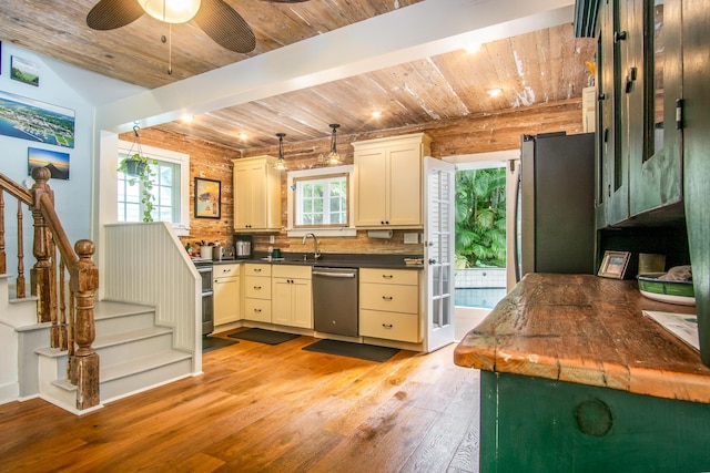 kitchen with sink, rustic walls, appliances with stainless steel finishes, wooden ceiling, and light wood-type flooring