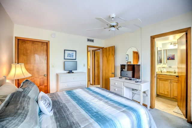 bedroom featuring ceiling fan, connected bathroom, visible vents, and light colored carpet