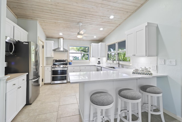 kitchen with appliances with stainless steel finishes, sink, a breakfast bar area, and wall chimney exhaust hood