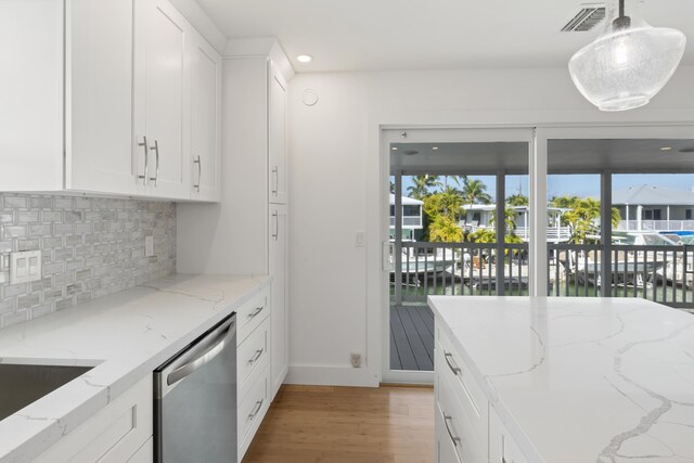 kitchen with hanging light fixtures, a water view, stainless steel dishwasher, and light stone counters