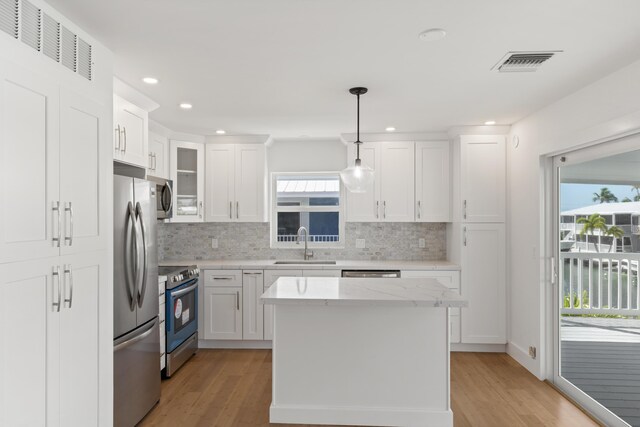 kitchen with pendant lighting, sink, white cabinetry, and appliances with stainless steel finishes