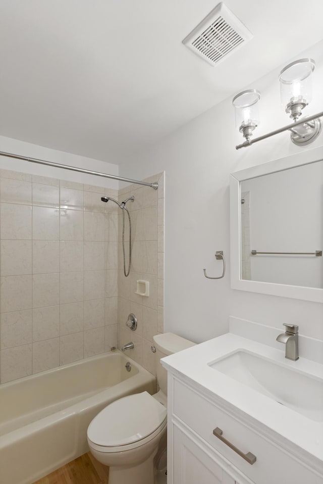 full bathroom with vanity, hardwood / wood-style flooring, toilet, and tiled shower / bath