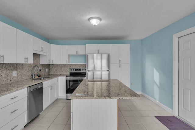 kitchen with a kitchen island, appliances with stainless steel finishes, sink, backsplash, and light stone counters