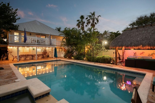 pool at dusk with outdoor lounge area, a jacuzzi, and a patio area