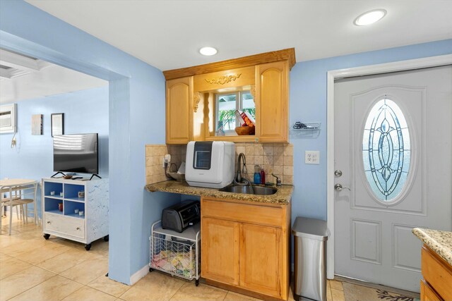 kitchen featuring tasteful backsplash, sink, light stone counters, and light tile patterned floors