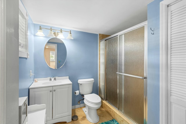 bathroom featuring vanity, toilet, a shower with shower door, and tile patterned flooring