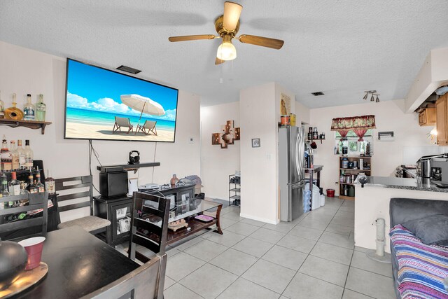 living room featuring ceiling fan, light tile patterned floors, and a textured ceiling