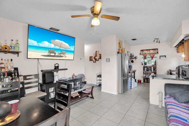 living room featuring ceiling fan, light tile patterned floors, and a textured ceiling