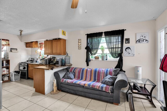 living room with a textured ceiling, ceiling fan, and light tile patterned flooring