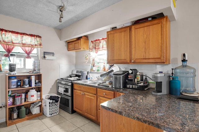 kitchen featuring double oven range, light tile patterned floors, a textured ceiling, and plenty of natural light