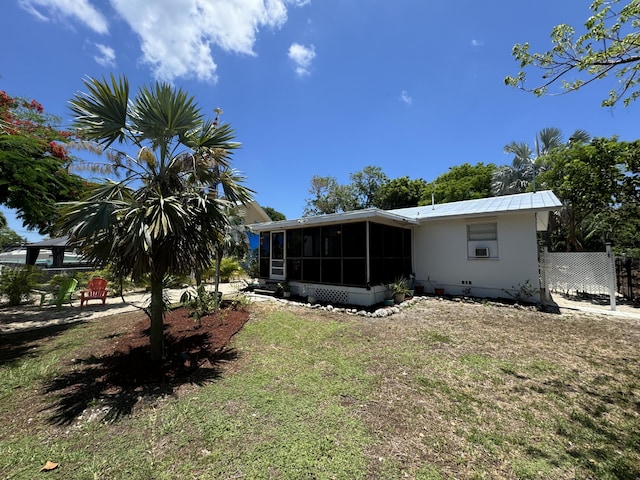 back of property featuring a lawn and a sunroom